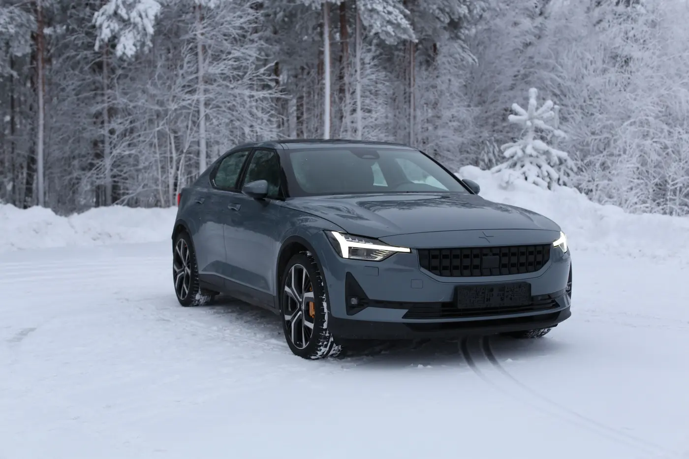 Harmaa Polestar 2 lumisessa metsässä